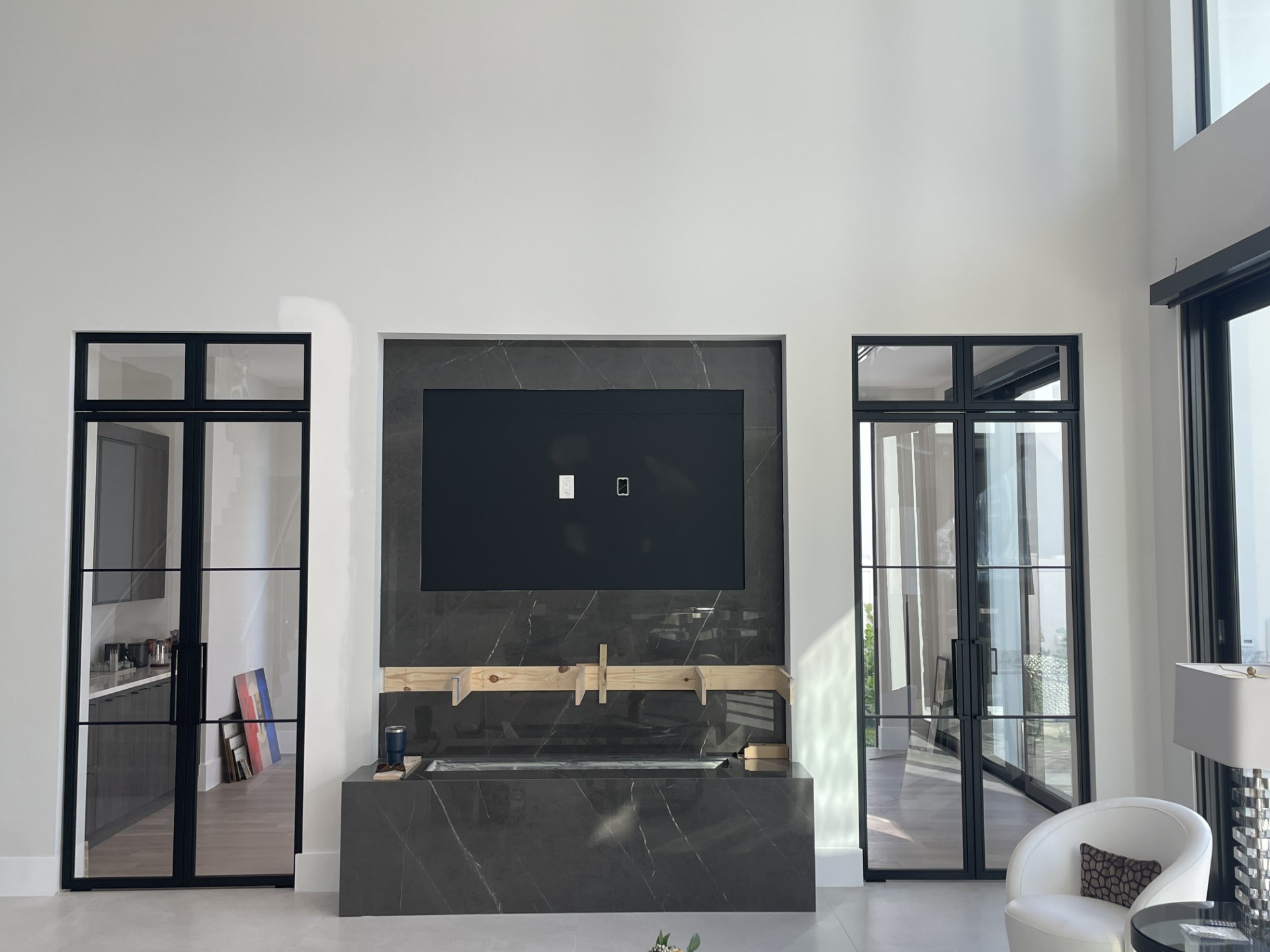 Black-framed glass partition doors flanking a media wall by RG Glass