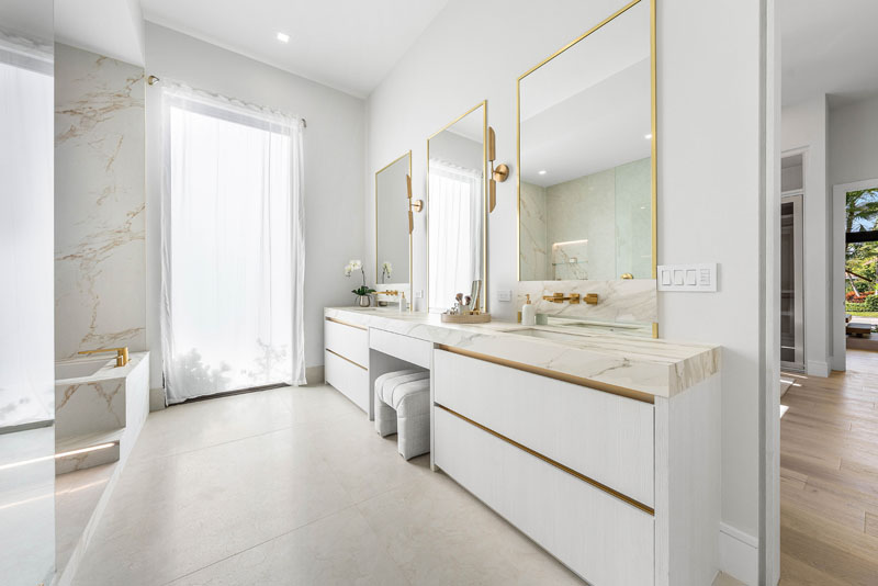 Triple gold-framed custom glass mirrors above double vanity by RG Glass